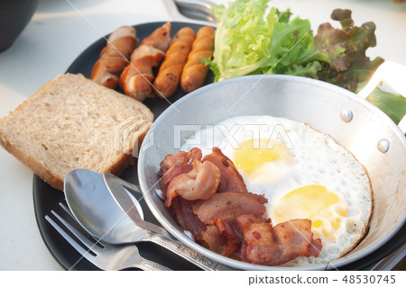 Fried eggs, bacon and sausage on pan. Breakfast 48530745