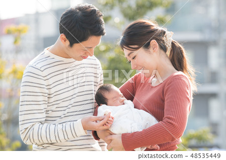 A young couple holding a baby Child-raising family newborn 48535449