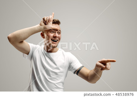 Losers go home. Portrait of happy guy showing loser sign over forehead Losers go home. Portrait of happy guy showing loser sign over forehead 48538976