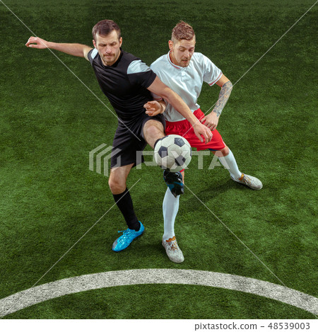 Football players tackling ball over green grass background Football players tackling ball over green grass background 48539003