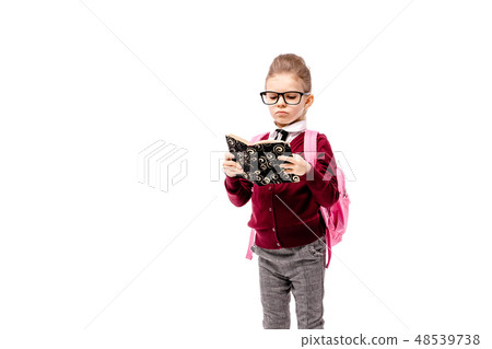 Child with schoolbag. Girl in white shirt and gray pants, rounded glasses, hold a book, school bag 48539738
