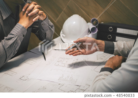 Construction engineering or architect discuss a blueprint while 48540833