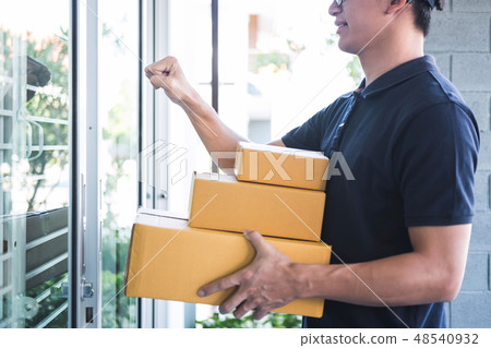 Delivery man standing with parcels in hands outdoors waiting hom Delivery man standing with parcels in hands outdoors waiting hom 48540932