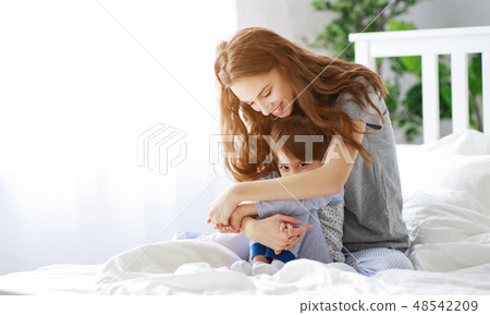 happy family mother and child cuddling in bed. happy family mother and child cuddling in bed. 48542209