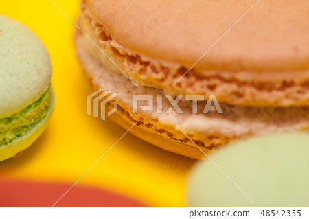 Close up big macaroon caramel flavour next to little macaroons over yellow background Close up big macaroon caramel flavour next to little macaroons over yellow background 48542355