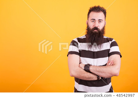 Handsome bearded man with stripped t-shirt holding arms crossed and looking at the camera over Handsome bearded man with stripped t-shirt holding arms crossed and looking at the camera over 48542997