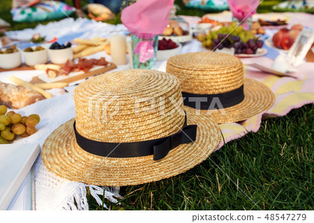 straw hats lay on a white picnic blanket at green  48547279