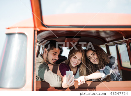 A group of young friends on a roadtrip through countryside, taking selfie. A group of young friends on a roadtrip through countryside, taking selfie. 48547734