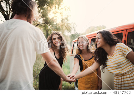 A group of young friends on a roadtrip through countryside, putting hands together. 48547763
