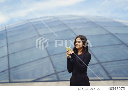 brunette girl using her cellphone as she is exploring a new city 48547975