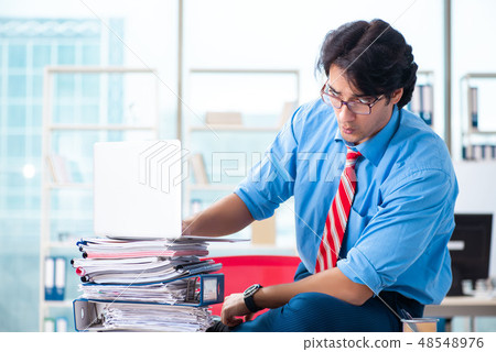 Handsome businessman unhappy with excessive work in the office Handsome businessman unhappy with excessive work in the office 48548976