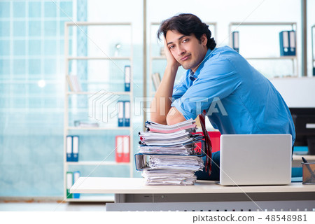 Handsome businessman unhappy with excessive work in the office Handsome businessman unhappy with excessive work in the office 48548981