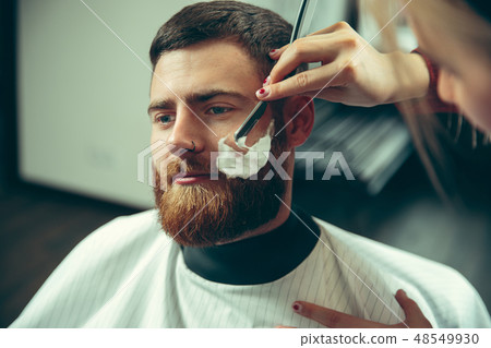 Client during beard shaving in barber shop 48549930