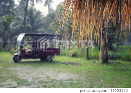 Strong tropical rain in the village on the background of a motorcycle Strong tropical rain in the village on the background of a motorcycle 48553323
