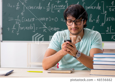 Young male student mathematician in front of chalkboard  48556882