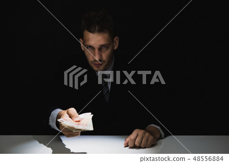 Tricky sly businessman giving money in the dark Tricky sly businessman giving money in the dark 48556884
