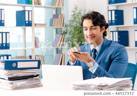 Young handsome male employee with too much work in the office   48557337
