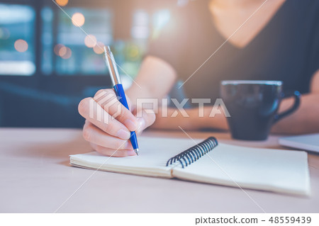 Business woman's hand is writing on a notebook Business woman's hand is writing on a notebook 48559439