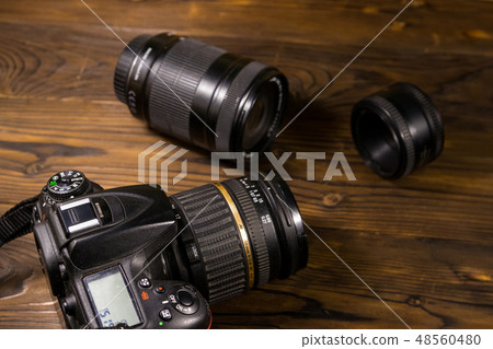Modern photo camera and photo lenses on wood table Modern photo camera and photo lenses on wood table 48560480