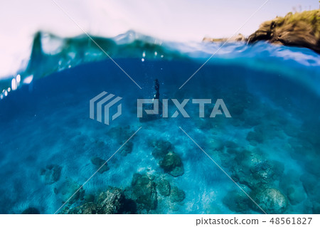 Freediver in wetsuit dive at depth in the blue sea 48561827