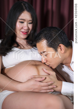 Husband kissing to his wife's belly on bed 48564498