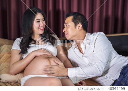 Pregnant women with her husband feeling happy on bed Pregnant women with her husband feeling happy on bed 48564499