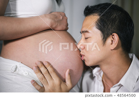 Husband kissing to his wife's belly 48564500