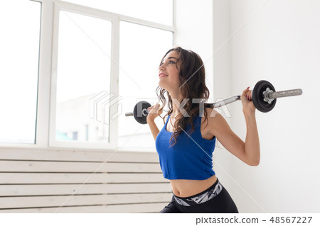 Fitness, sport and people concept - smiling sporty woman with barbell doing split squat or lunge 48567227