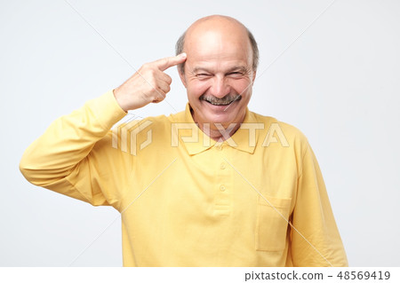 senior man smiling pointing to head with finger senior man smiling pointing to head with finger 48569419