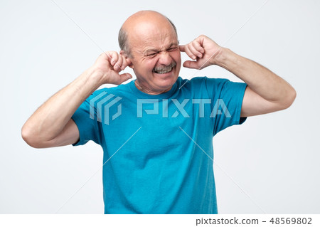 Senior hispanic bald guy plugging ears with finger Senior hispanic bald guy plugging ears with finger 48569802