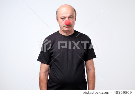 Mature businessman wearing clown nose Mature businessman wearing clown nose 48569809
