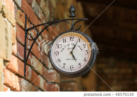 Old city street clock on a house wall Old city street clock on a house wall 48570130