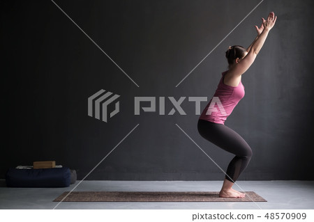 Woman practicing yoga, doing Chair exercise 48570909