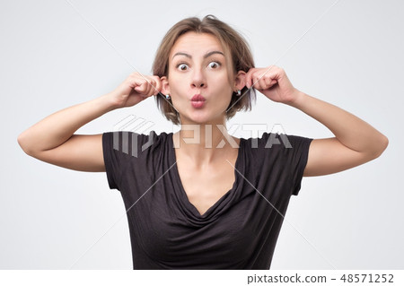 beautiful young woman pulling herself by the ears 48571252