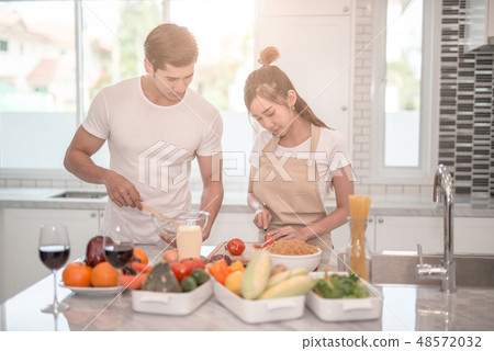asian couple cooking together in the kitchen 48572032