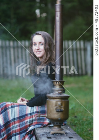 Russian woman sitting near the samovar 48572403