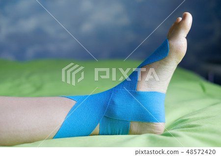 Elastic therapeutic tape applied to patient leg. 48572420