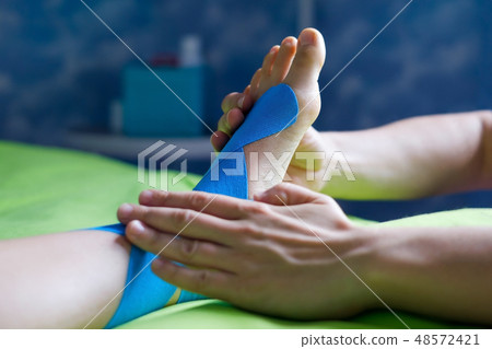 Doctor taping woman injury leg. 48572421