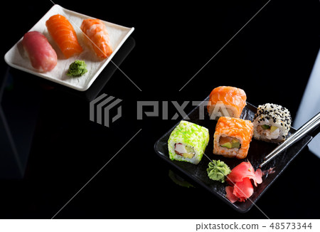 Large sushi sets with lots of sushi, roll . Stylish sushi sets on a black ceramic plane and table Large sushi sets with lots of sushi, roll . Stylish sushi sets on a black ceramic plane and table 48573344