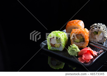 Large sushi sets with lots of sushi, roll . Stylish sushi sets on a black ceramic plane and table 48573345