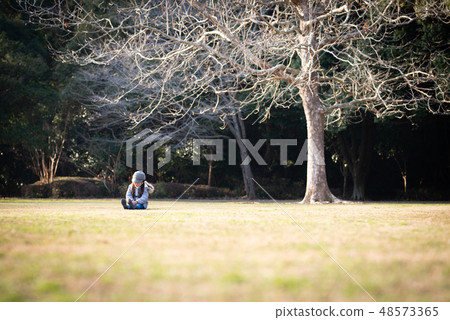 坐在一個公園的女孩在冬天 48573365