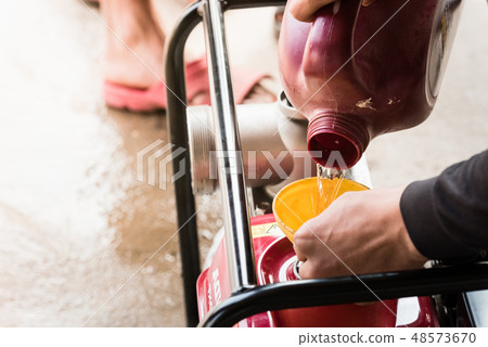 Farmer fill fuel into water pump engine 48573670
