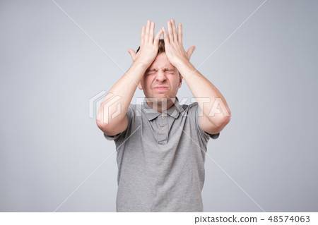 man holding hands on head and closing his eyes man holding hands on head and closing his eyes 48574063