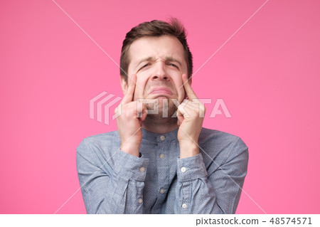 sad young man crying on pink background 48574571