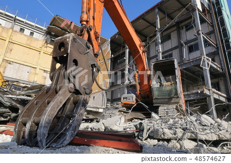 拆除作業現場及配備抓斗機的液壓挖土機 拆除作業現場及配備抓斗機的液壓挖土機 48574627
