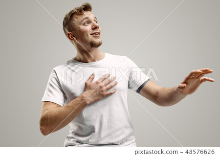 The young attractive man looking suprised isolated on gray The young attractive man looking suprised isolated on gray 48576626