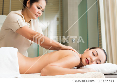 Body Massage on naked back of Mix Race Caucasian Asian woman by pressing fingers on pain or stress muscle point to release relax. Therapist Spa body massage woman hands treatment on customer Body Massage on naked back of Mix Race Caucasian Asian woman by pressing fingers on pain or stress muscle point to release relax. Therapist Spa body massage woman hands treatment on customer 48576754