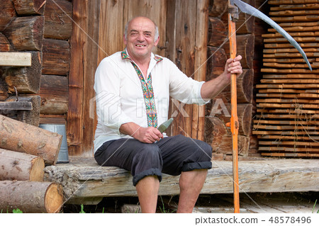 Senior man in hutsul clothes with scythe. 48578496