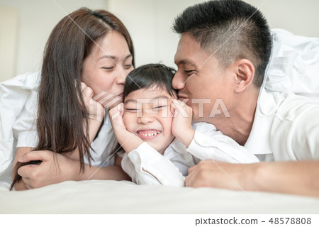 Asian Parents kissing their little son on both che Asian Parents kissing their little son on both che 48578808