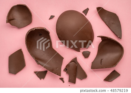 exploded chocolate Easter egg over pink background exploded chocolate Easter egg over pink background 48579219